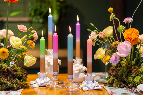 Velas Hygge Gold dispostas decorativamente com flores e castiçais